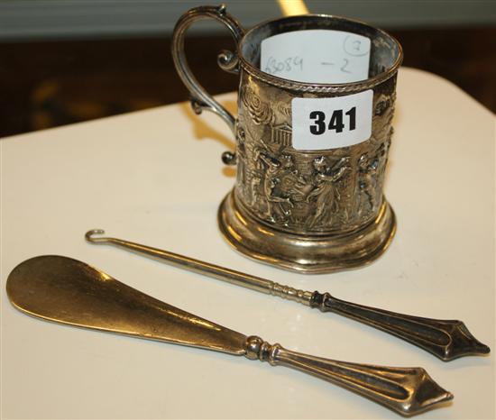 An embossed silver christening mug, a shoe horn and a button hook